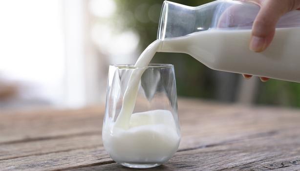 Jarra y vaso con un tipo de leche sobre una mesa de madera