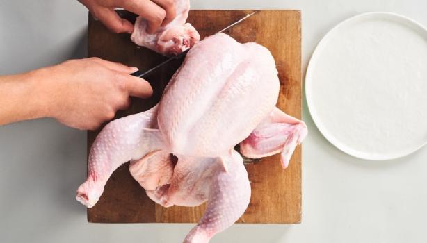 Corte de la carcasa de pollo sobre una tabla de madera, ideal para usar en caldos de hueso de pollo