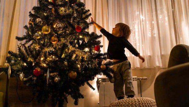 Niño pequeño poniendo decoración de navidad en el salón.