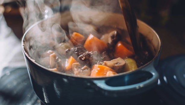 Olla vaporera cocinando guiso de verduras con carne.