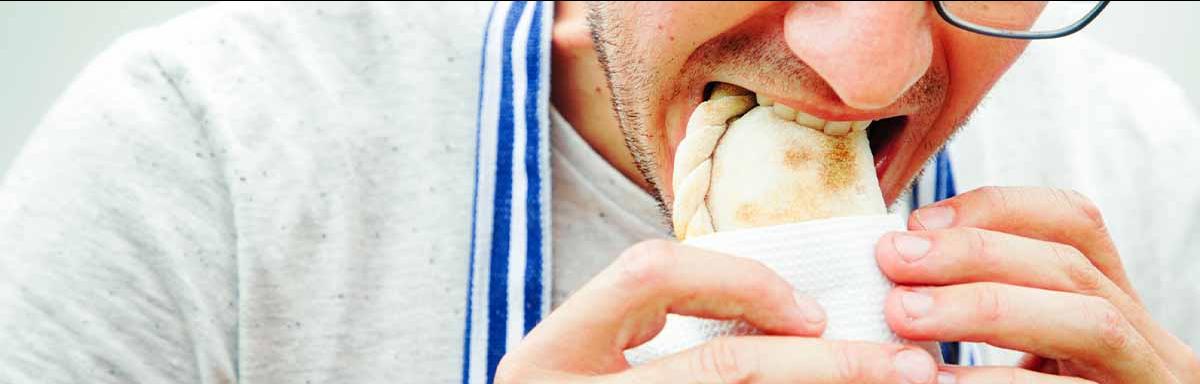 Un hombre comiendo una empanada tucumeña, una clase de empanada argentina.