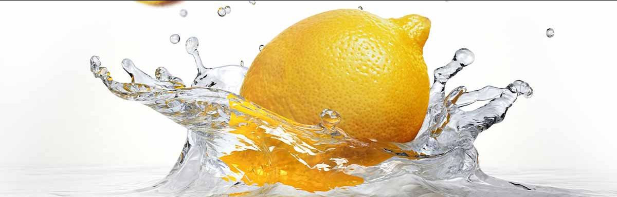 Un tipo de limón amarillo cayendo en el agua.