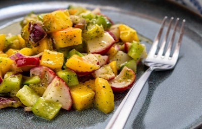 Una ensalada con mango y verduras, con su aderezo.