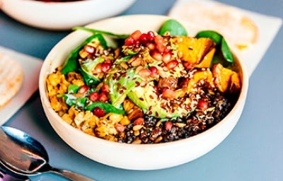 Granos, semillas, frutas y verduras en un plato de comida vegetariana.
