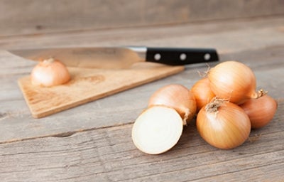 Cebollas sobre una mesa, listas para cortar en julianas o rodajas.