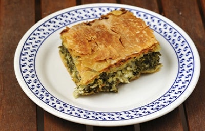 Una porción de la receta griega spanakopita sobre un plato blanco y azul