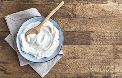 Un plato con yogurt casero recién preparado y una cucharita de madera