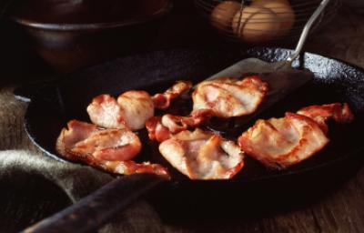 Pedazos de panceta fritos. Deliciosa panceta cortada siendo fritada en un sartén.