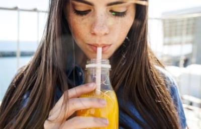 Jugo de zanahoria con limón, refrescante y beneficioso. Mujer bebiendo un refrescante jugo de zanahoria con limón.