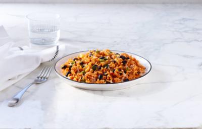 Arroz con habichuela, tradición en Centroamérica. Plato hondo de arroz con habichuela junto a un tenedor, vaso de agua y servilleta.