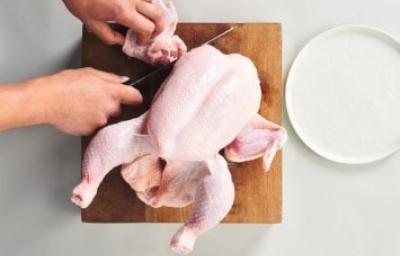Cómo cortar la carcasa de pollo para preparar caldos y sopas Corte de la carcasa de pollo sobre una tabla de madera, ideal para usar en caldos de hueso de pollo