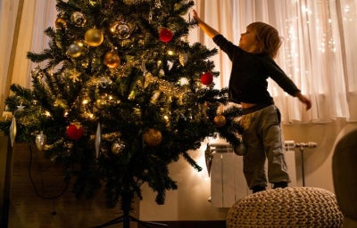 Niño pequeño poniendo decoración de navidad en el salón.
