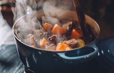 Olla vaporera cocinando guiso de verduras con carne.