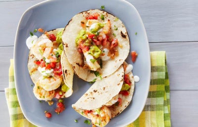 Plato con tres tacos de mariscos listos para ser degustados.