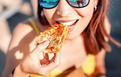 Chica feliz comiendo quesadilla de comida rápida mexicana en la playa. Un refrigerio saludable y delicioso.