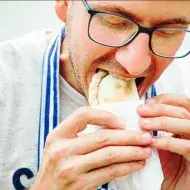 Un hombre comiendo una empanada tucumeña, una clase de empanada argentina.