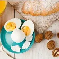 Huevos cocidos, acompañados por jugo de naranja y un croissant.