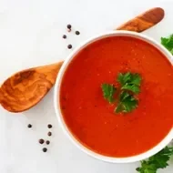 Crema de jitomate con perejil, una de las recetas más famosas, servida con una cuchara de madera.