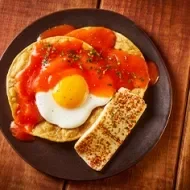 Un desayuno con huevo, tortillas y salsa. 
