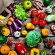 Múltiples frutas y verduras regadas sobre una mesa, que son alimentos que aportan vitaminas esenciales