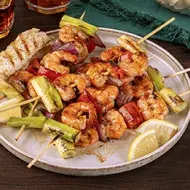 Pinchos con camarones y langostinos al ajillo con verduras y rodajas de limón mandarino