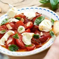 Ensalada caprese con tomate, queso, albahaca y pan en un plato.