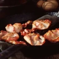 Deliciosa panceta cortada siendo fritada en un sartén.
