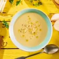 Vichyssoise en un tazón, mesa amarilla con ingredientes frescos