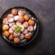 Plato de buñuelos de yuca espolvoreados vistos desde un ángulo cenital.
