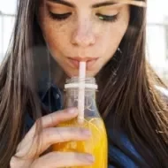 Mujer bebiendo un refrescante jugo de zanahoria con limón.