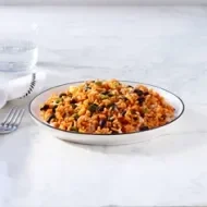 Arroz con habichuela, tradición en Centroamérica. Plato hondo de arroz con habichuela junto a un tenedor, vaso de agua y servilleta.