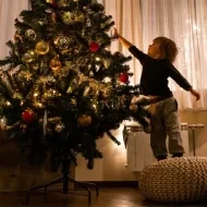 Niño pequeño poniendo decoración de navidad en el salón.