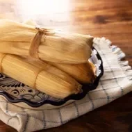 Plato con tres tamales de pescado envueltos perfectamente.
