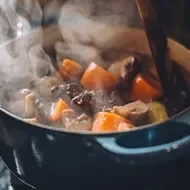 Olla vaporera cocinando guiso de verduras con carne.