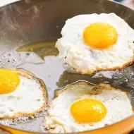 Sartén con tres huevos fritos cocinándose para acelerar metabolismo.