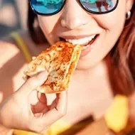 Chica feliz comiendo quesadilla de comida rápida mexicana en la playa. Un refrigerio saludable y delicioso.