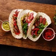 Fajitas de bistec a la parrilla con tortillas de taco y salsa, el origen de los tacos.